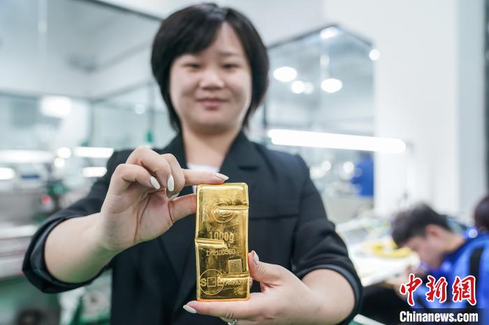 图为广西凤锦珠宝有限公司总经理助理贺彩玲向记者展示一块1000克的金条。　陈冠言 摄